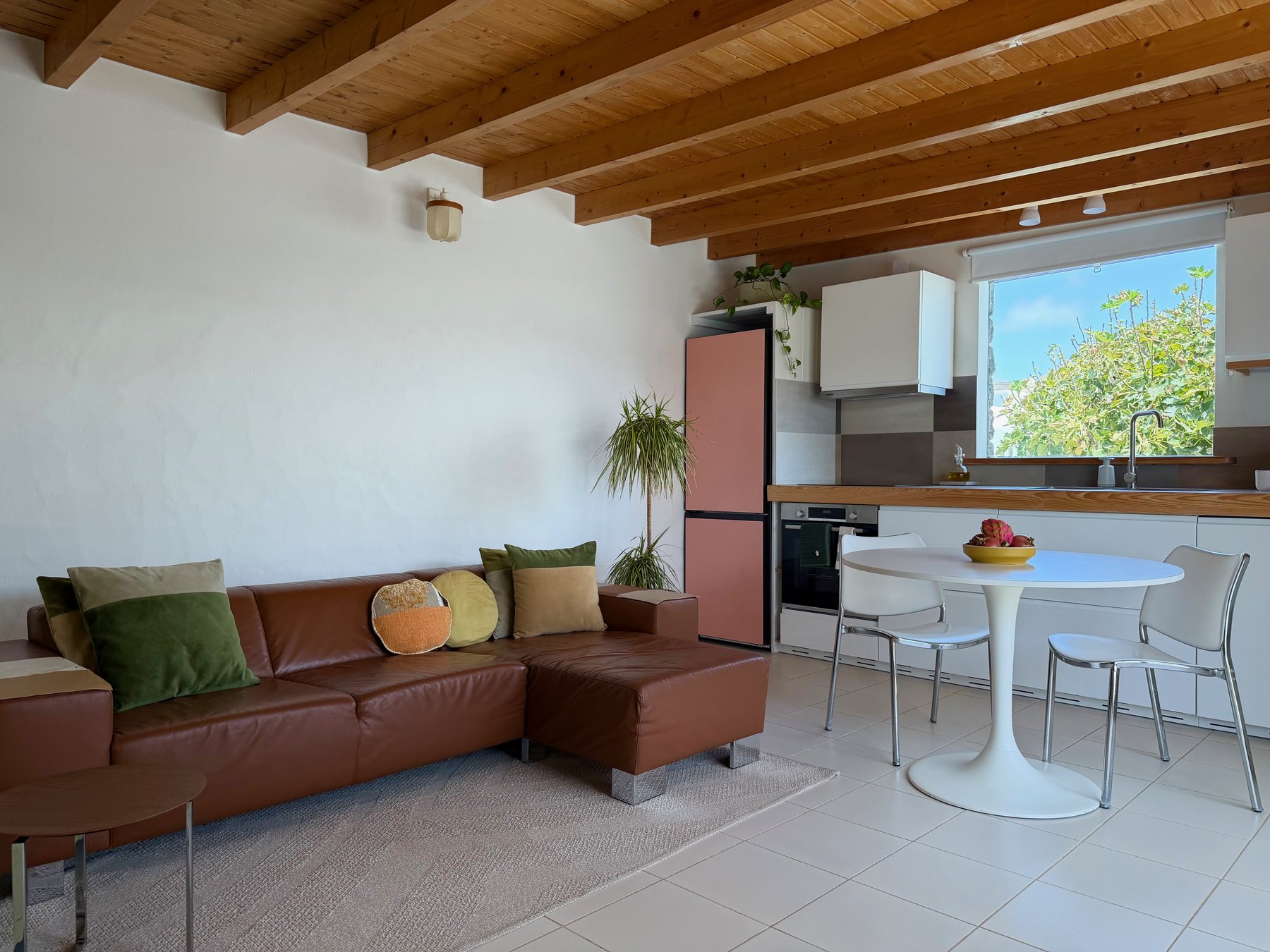 The lounge and kitchen under the beamed ceiling, with the leather sofa